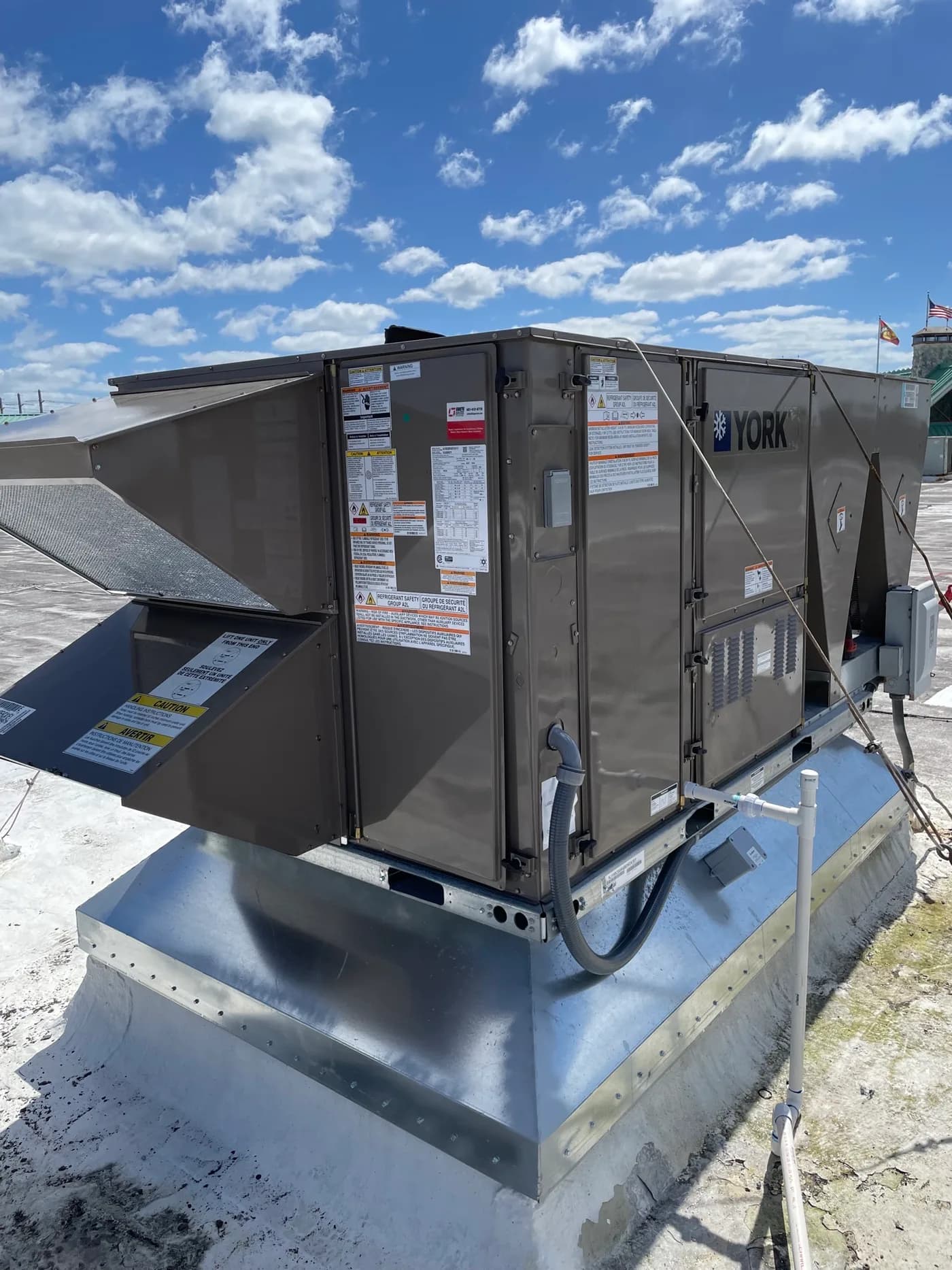 Completed YORK commercial rooftop unit with electrical disconnect and condensate drain on a flat roof